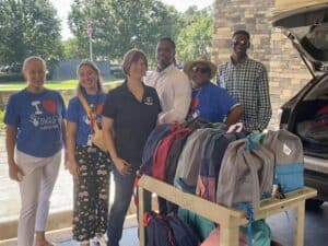 Volunteers stand with donated backpacks