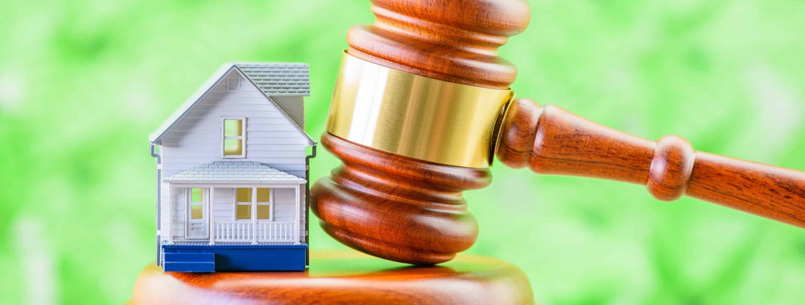 A small model house and a judge's gavel placed near each other